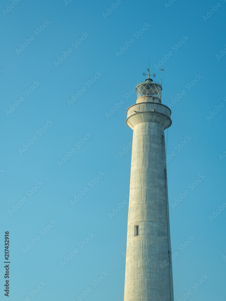 A white lighthouse set against a blue sky in the summer