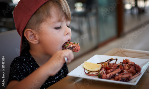Young boy eating octopus