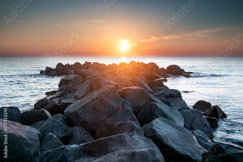 Colorful seascape ocean sunset with rocks ans sun lens flare and texture. Danish Coastline. Lonstrup in North Jutland in Denmark, Skagerrak, North Sea photo