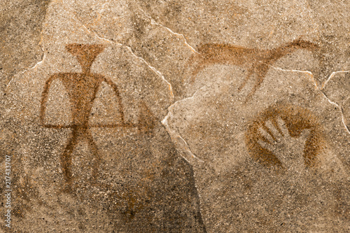 image of an ancient man with a gun, an animal, a palm print on the cave wall.