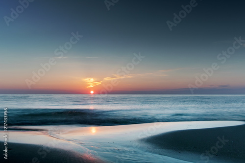 sunset reflection in the ocean water on a lovely empty beach in summer holidays. Danish Coastline. Lonstrup in North Jutland in Denmark, Skagerrak, North Sea