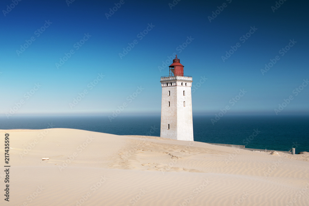 Bright beach sand dunes with the famous danish landmark lighthouse with blue sky background. Rubjerg Knude Lighthouse, Lønstrup in North Jutland in Denmark, Skagerrak, North Sea