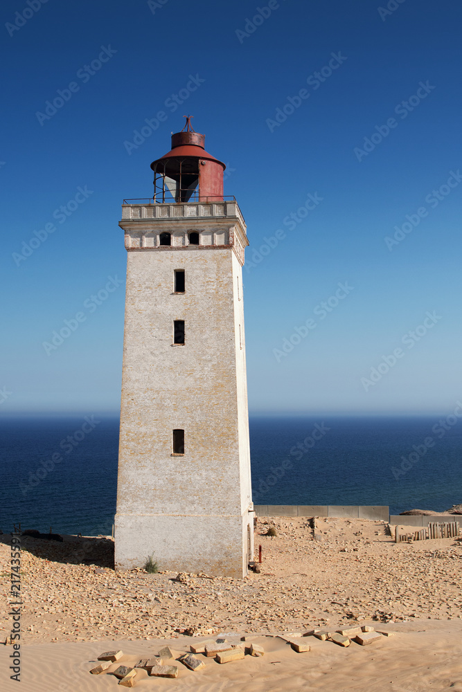 Bright beach sand dunes with the famous danish landmark lighthouse with blue sky background. Rubjerg Knude Lighthouse, Lønstrup in North Jutland in Denmark, Skagerrak, North Sea