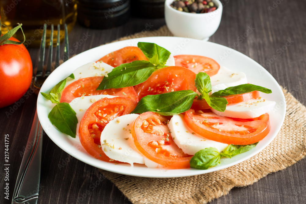 Close-up photo of caprese salad with ripe tomatoes, basil, buffalo mozzarella cheese. Italian and Mediterranean food concept. Fresh and healthy organic meal. Starter and antipasti. 