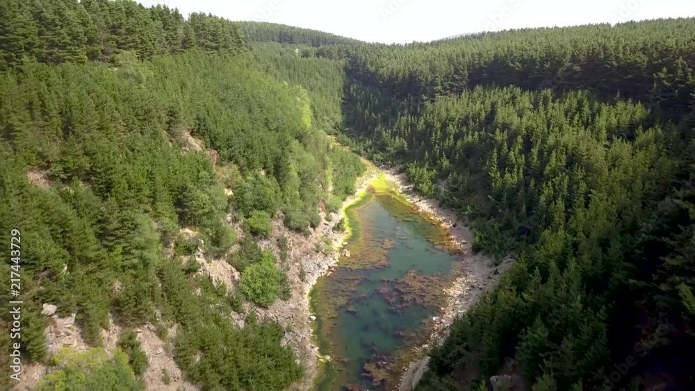 Aerial drone view flying backwards over a narrow, long lake and onto a forested area at the top of a canyon Aerial drone view flying backwards over a narrow, long lake and onto a forested area at the top of a canyon