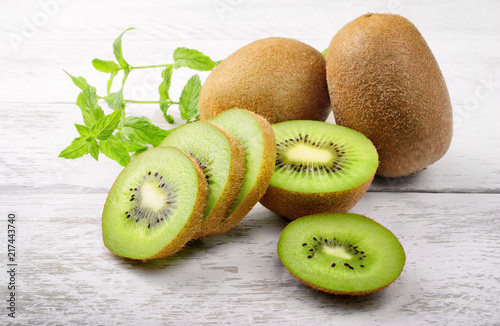 Green kiwi and mint leaves on white wood background