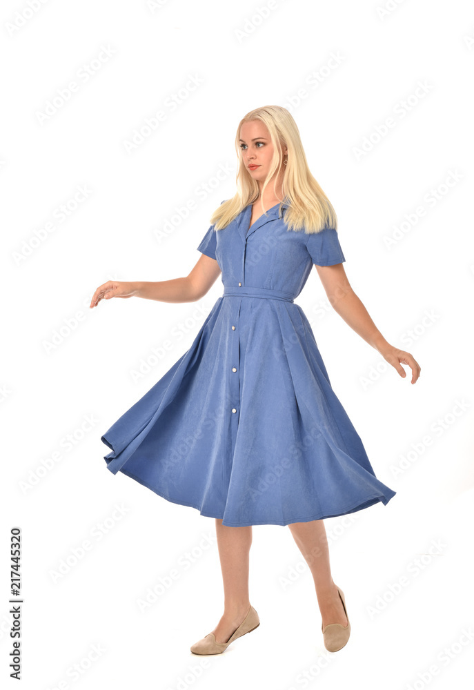 full length portrait of blonde girl wearing blue dress. standing pose. isolated on white  studio background.