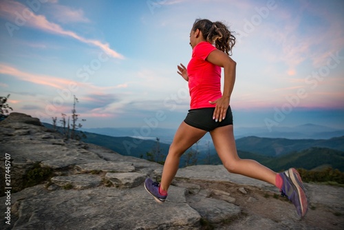 Woman running on rocks. Female cross country running in mountains.
