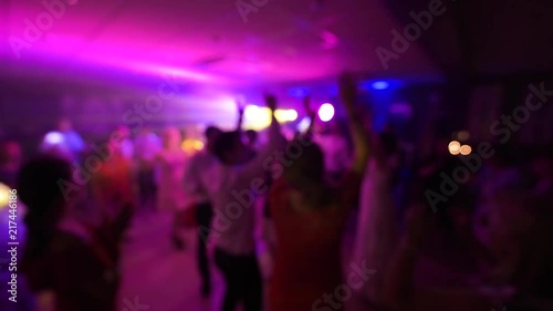 Disco party all night long with defocused view of great wedding party with silhouettes of people dancing on the dancefloor with blue disco lights glowing in the background multiple colors