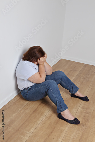 femme ronde pleurant contre un mur