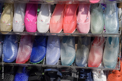 Rubber and silicone sandals and sneakers on the shoe shelf in the market.