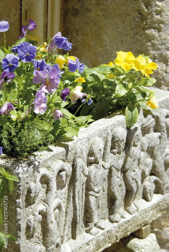 Fleurs violettes et jaune dans une balconière en pierre sculptée photo