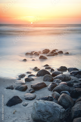 Calm long exposure ocean seascape with stones and the beach during colorful sunset twilight. Danish coastline, Lønstrup in North Jutland in Denmark, Skagerrak, North Sea