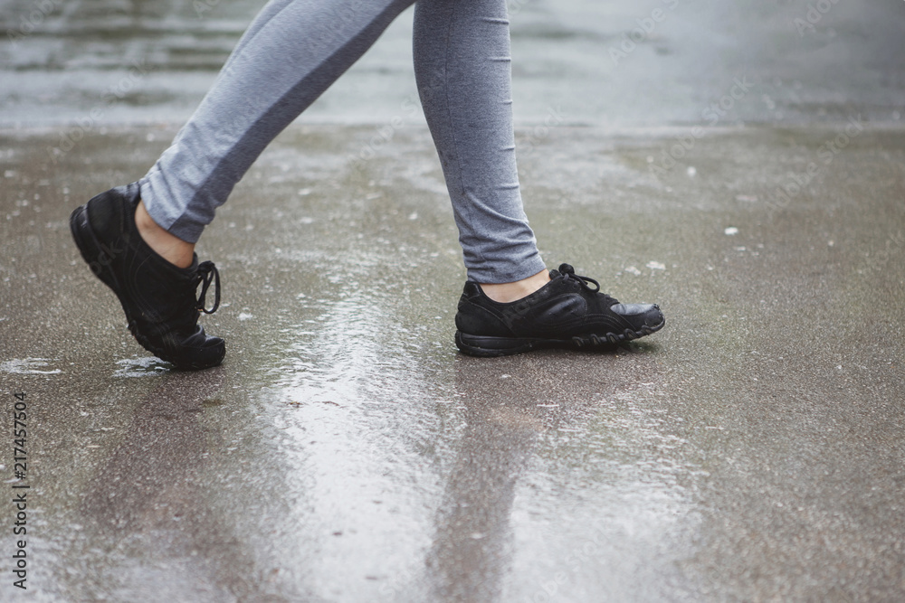 Legs of a girl in gray pants and black sneakers during a run in the summer green park. Legs of a girl in gray pants and black sneakers during a run in the summer green park.