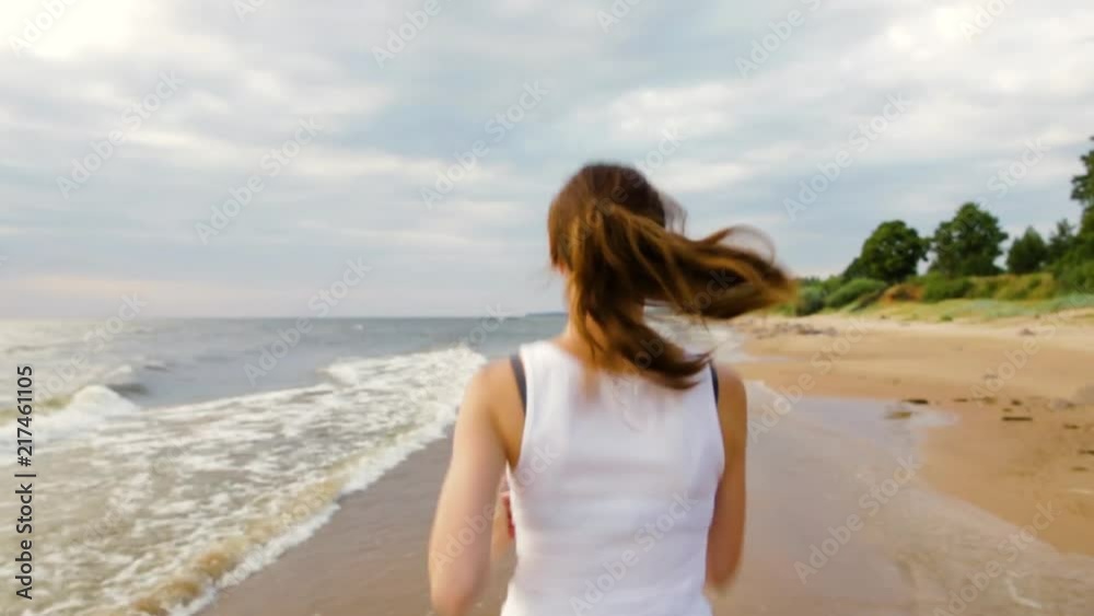 Woman running by the sea coastline on beautiful evening. Running motion. Healthy lifestyle concept Woman running by the sea coastline on beautiful evening. Running motion. Healthy lifestyle concept