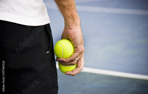 Tennis player holding two yellow balls on the court.