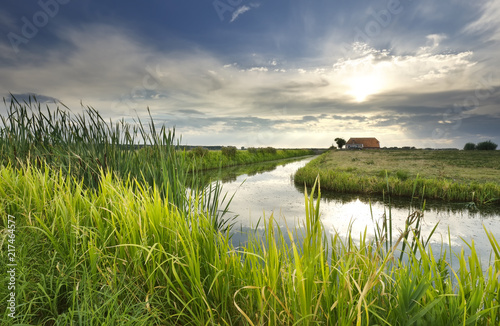 sunbeams over house, river and meadow photo