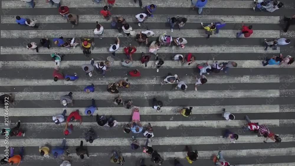 Vertical Video with aerial top view of a busy crosswalk intersection with people walking on both sides.