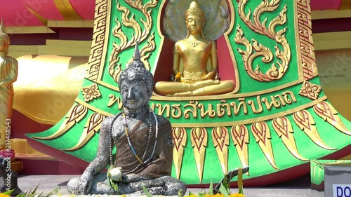 Close-up of stone and golden statues of Buddha sitting in Subduing Mara and Dhyana mudras. Gorgeous Buddhist religious sculptures in Wat Phra Yai temple, Koh Samui island, Thailand. Camera zooms out. photo