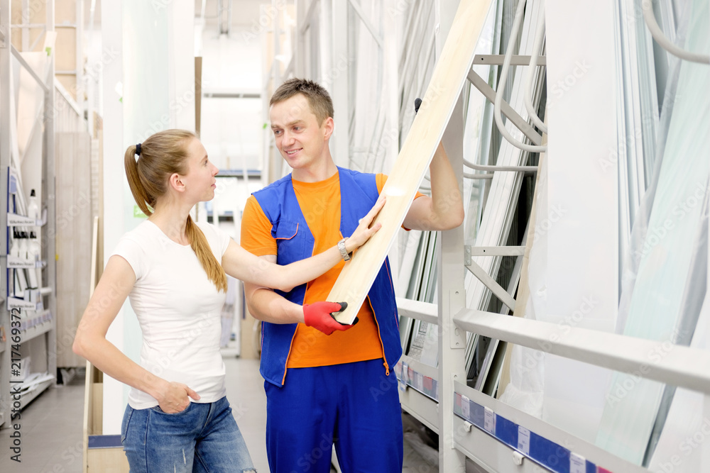 salesman in construction store offers goods to a woman client