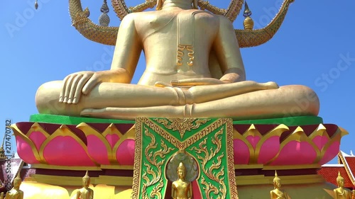 Panoramic view of golden statue of Big Buddha sitting in Subduing Mara or Bhumisparsa mudra illuminated by sun against blue sky on background. Wat Phra Yai temple, Koh Samui island, Thailand. photo
