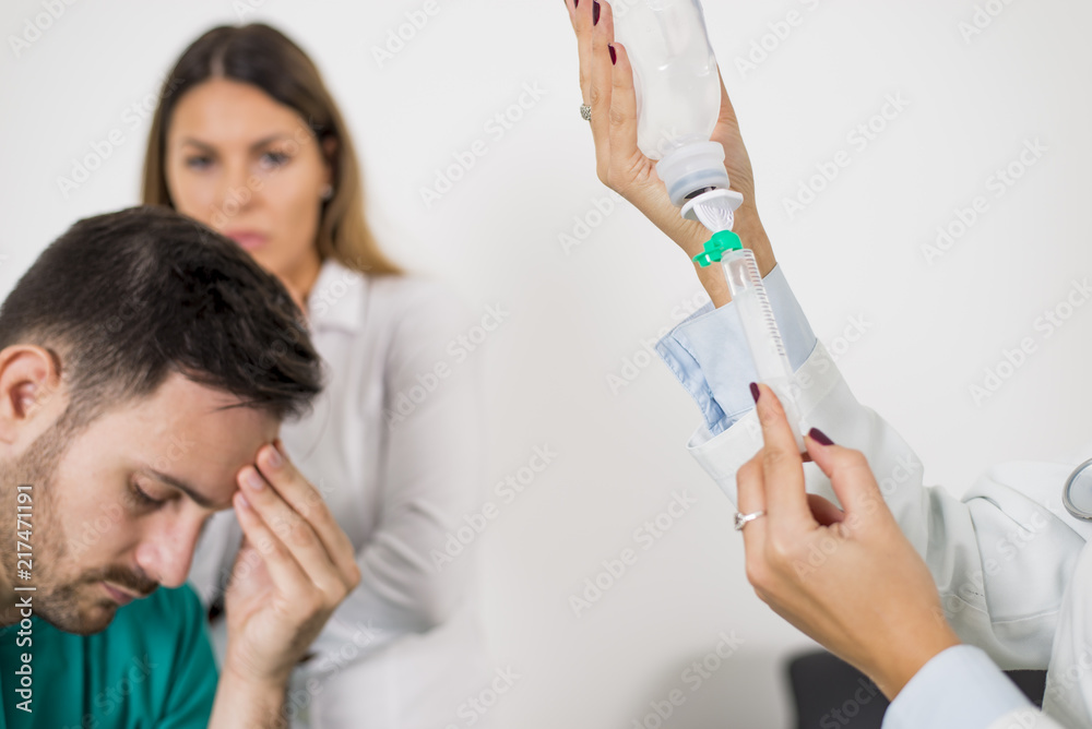 Female doctor prepares an injection while the patient is in bed Female doctor prepares an injection while the patient is in bed