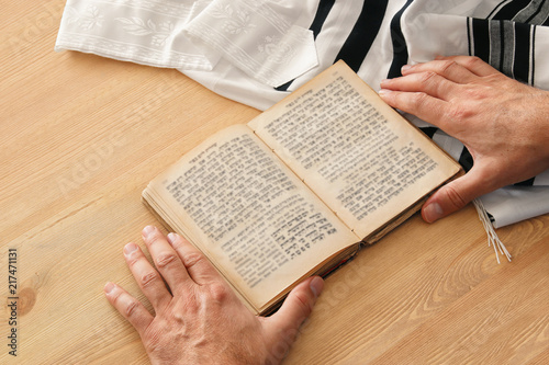 Jewish man hands holding a Prayer book, praying, next to tallit. Jewish traditional symbols. Rosh hashanah (jewish New Year holiday), Shabbat and Yom kippur concept.