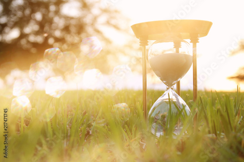 Hourglass in the grass time during sunset. vintage style.