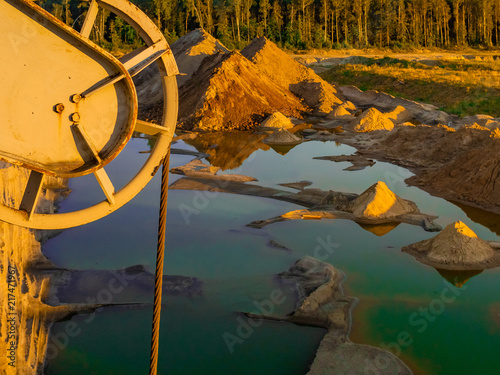 A view from above on a sandy quarry filled with water. photo from a drone. water is green. yellow sand at sunset. picture for the background. photo