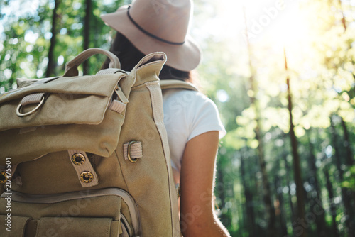 Back view on handsome traveler hipster girl with backpack and hat walking in forest among trees © leonidkos
