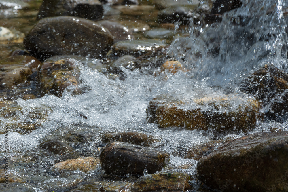 Wasser fliesst im Bach und spritzt Wasser fliesst im Bach und spritzt