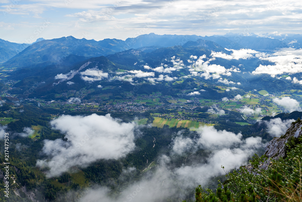 Alpine green fields and traditional wooden houses view of the Bad Goisern village at summer sunny day. A lot of clouds. Location:  village Bad Goisern, Salzkammergut region, in Upper Austria