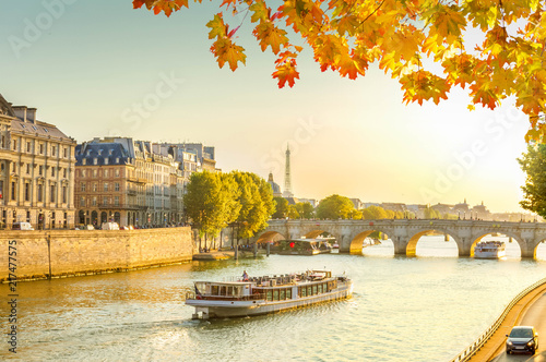 bridge Pont Neuf and Seine river with floating ship at sunny autumn sunset, Paris, France, toned