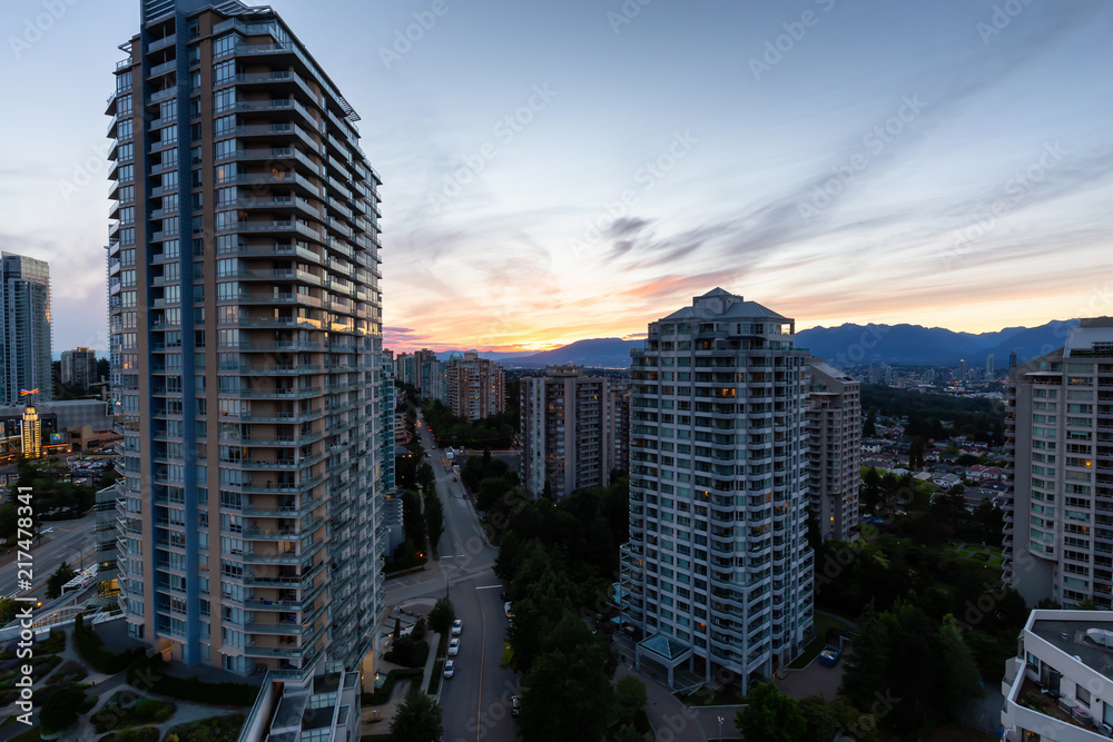 Obraz premium Metrotown, Burnaby, Vancouver, BC, Canada - June 26, 2018: Aerial view of Residential Homes near Metropolis Shopping Mall during a vibrant summer sunset.