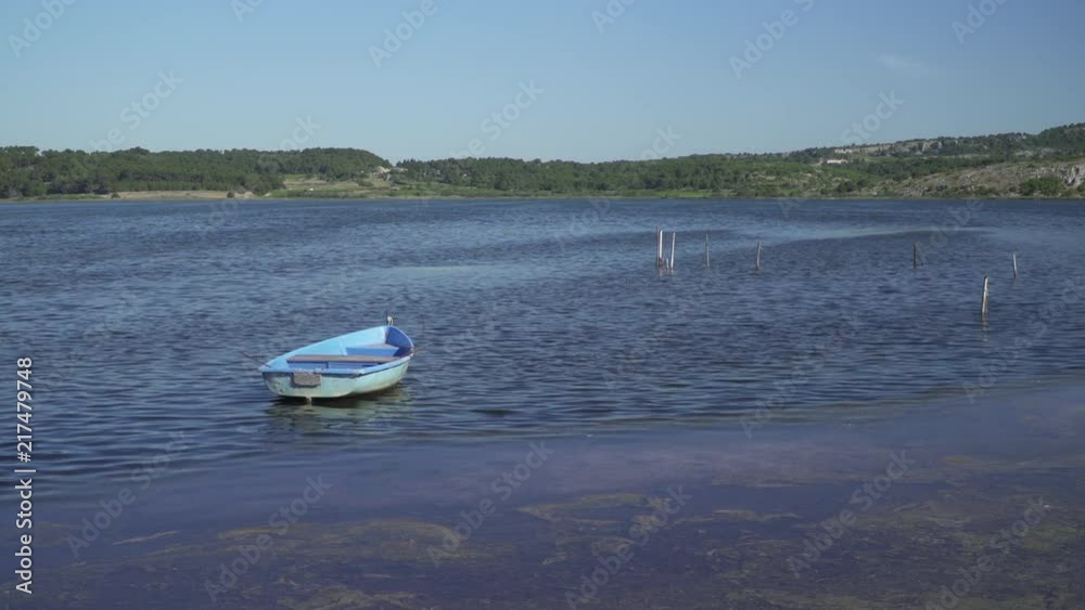 A tiny fishing boat on an inland lake at the mediterranean coast of France, Languedoc A tiny fishing boat on an inland lake at the mediterranean coast of France, Languedoc