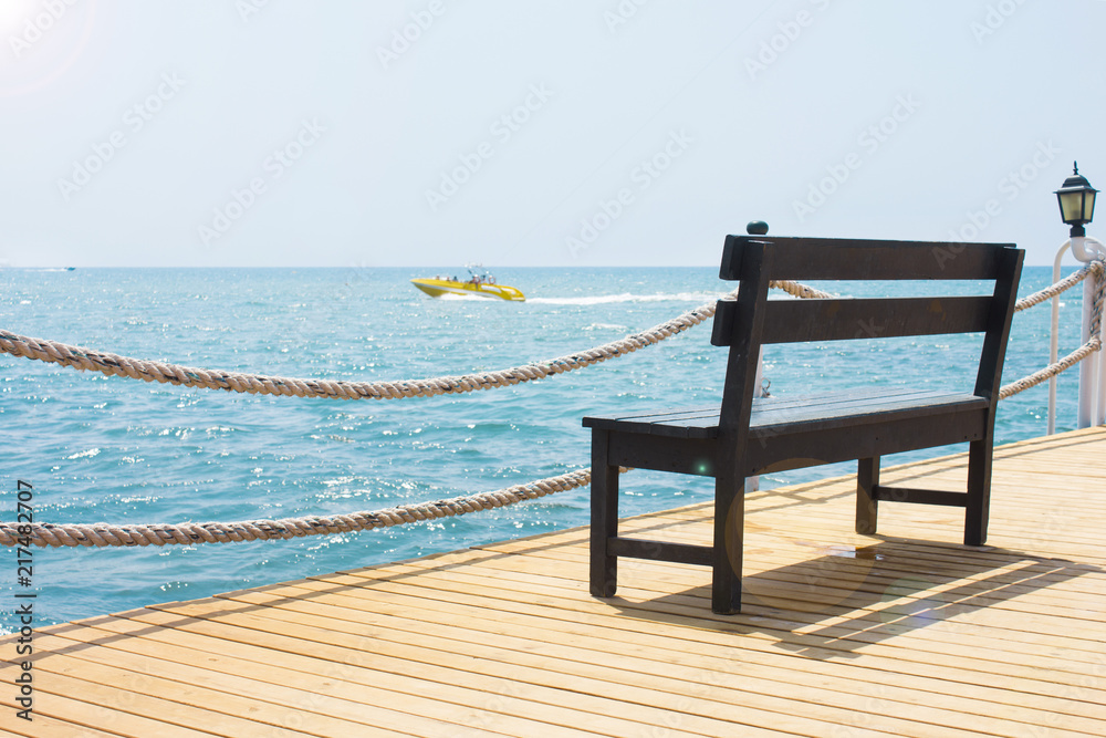 Wooden bench on the pier by the sea with a boat