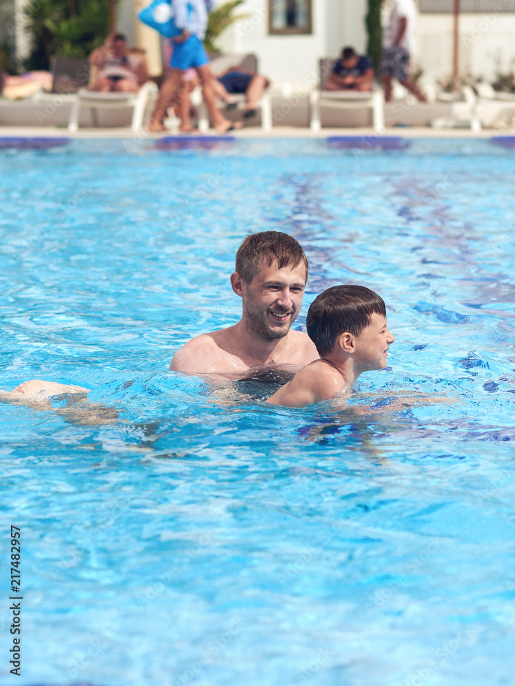 Father is helping his son to obtain the swimming skills.