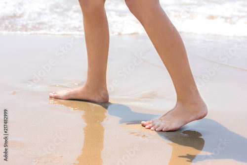 Bare feet walking at sandy beach near by the sea