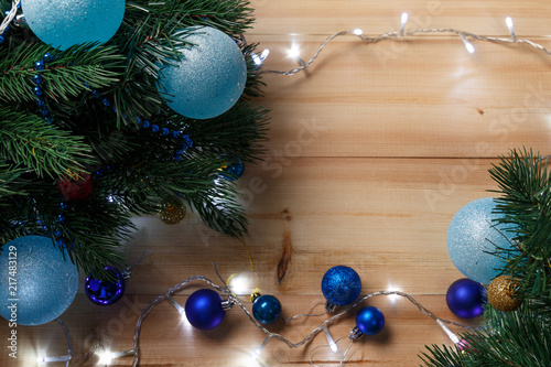 Christmas or New Year decoration background: fur-tree branches, colorful glass balls on wooden background. Christmas composition. Flat lay. Top view. Copy space. Christmas decorations