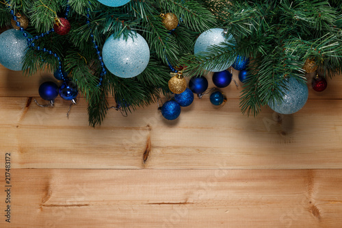 Christmas or New Year decoration background: fur-tree branches, colorful glass balls on wooden background. Christmas composition. Flat lay. Top view. Copy space. Christmas decorations