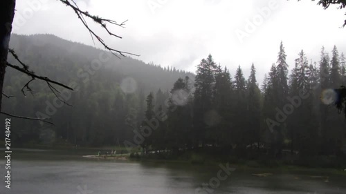 Rain over the mountain lake Synevyr. Drops of rain fall on the lens photo