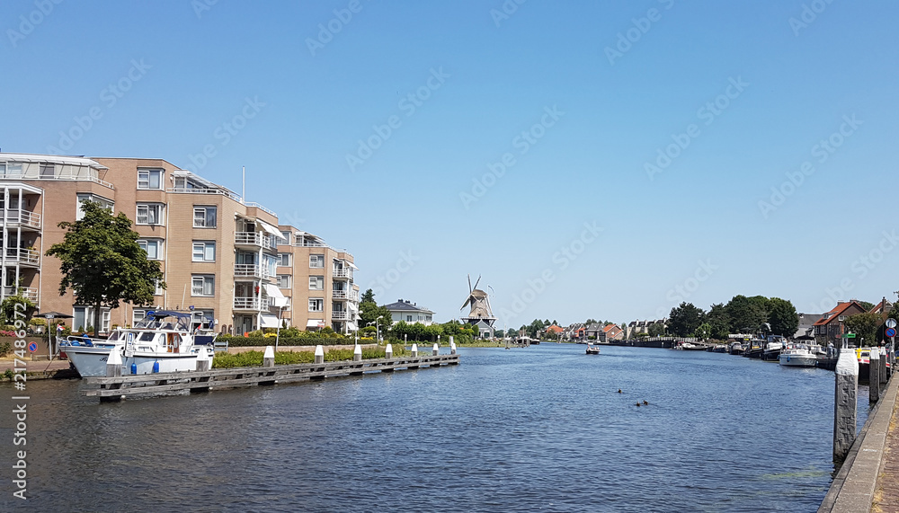River Vliet in Leidschendam with blue sky and windmill Salamander on the background in the Netherlands.