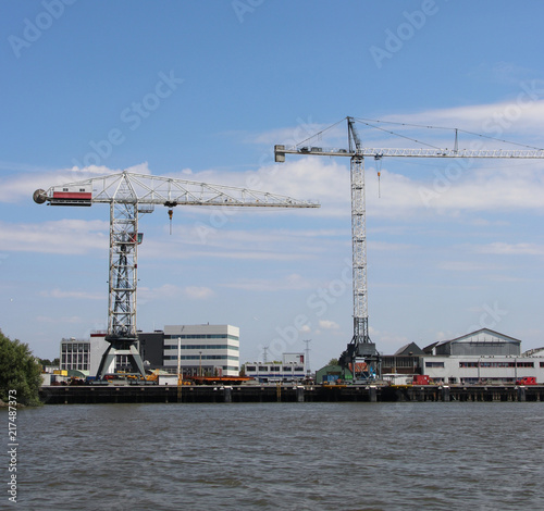 Docks with ships and cranes along the riverside of the river Lek or Noord in the Netherlands
