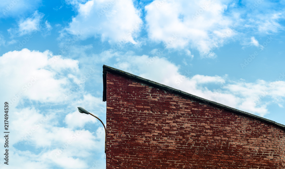 fragment of a brick building with a lantern against a blue sky w