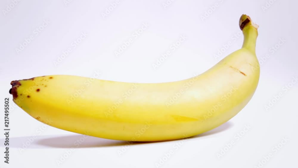 A single ripe yellow banana on a rotating surface. Front shot.
