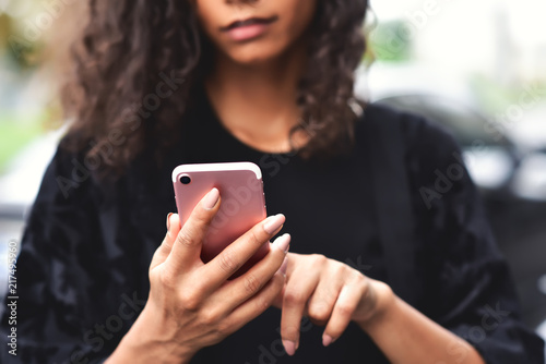 Closeup image of a beautiful mixed race woman holding, using and looking at smart phone with feeling happy.