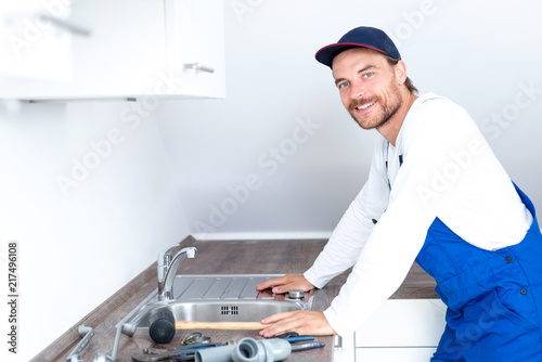 Installateur / Klempner positiv lächelnd bei der Arbeit in einer Küche 