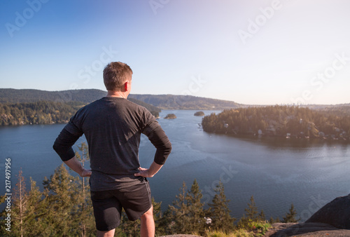 A jogger looking out from the top of a mountain onto the ocean. photo