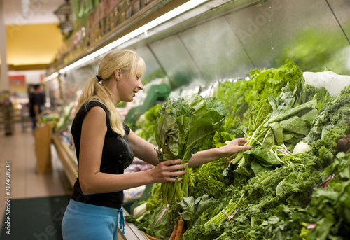  woman holding vegetables in supermarket 