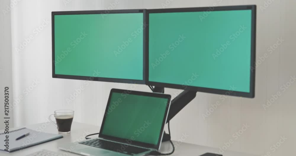 The laptop is connected to two monitors. The display screens have a